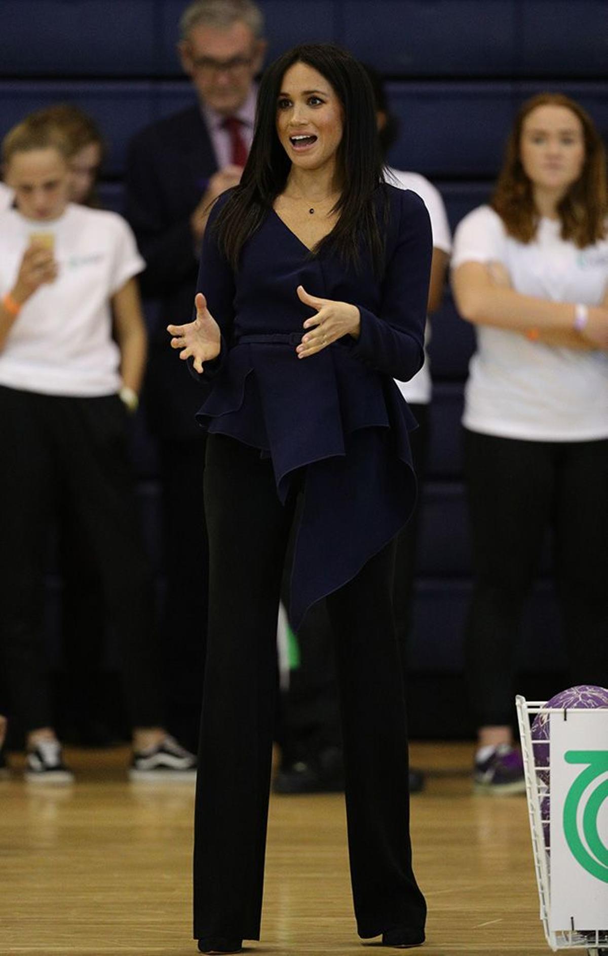 Meghan Markle en un evento con top péplum y pantalón oscuro