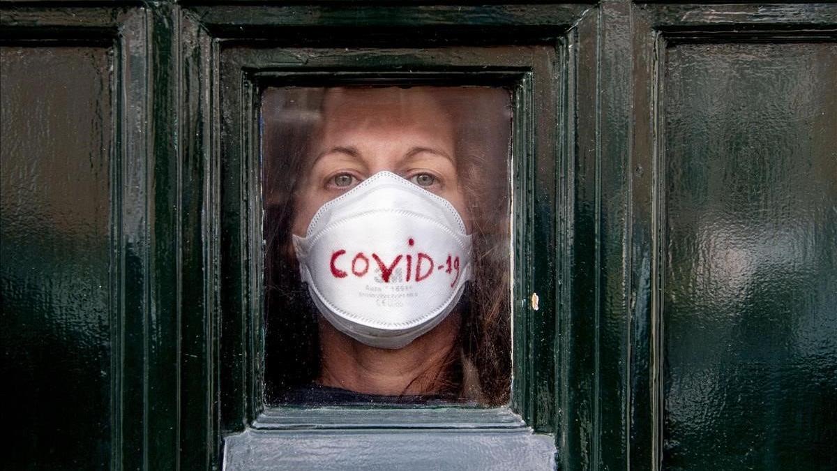 Una mujer mira al exterior desde la puerta de su casa,  en La Haya, donde permanece en cuarentena por el coronavirus.