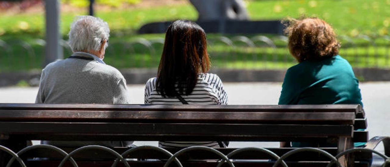 Tres personas charlan en un banco del Parque San Telmo de la capital grancanaria.