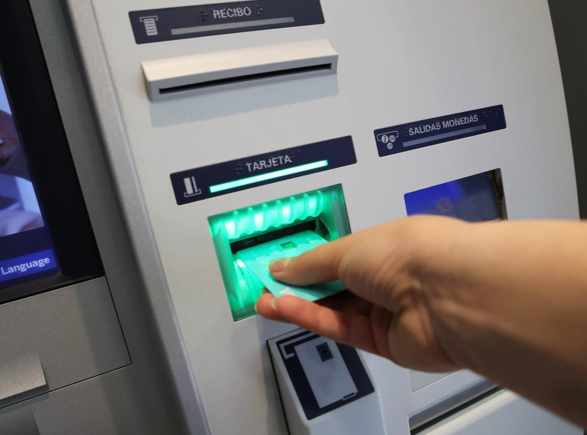 Una mujer retira dinero de un cajero automático. // ALBA VILLAR