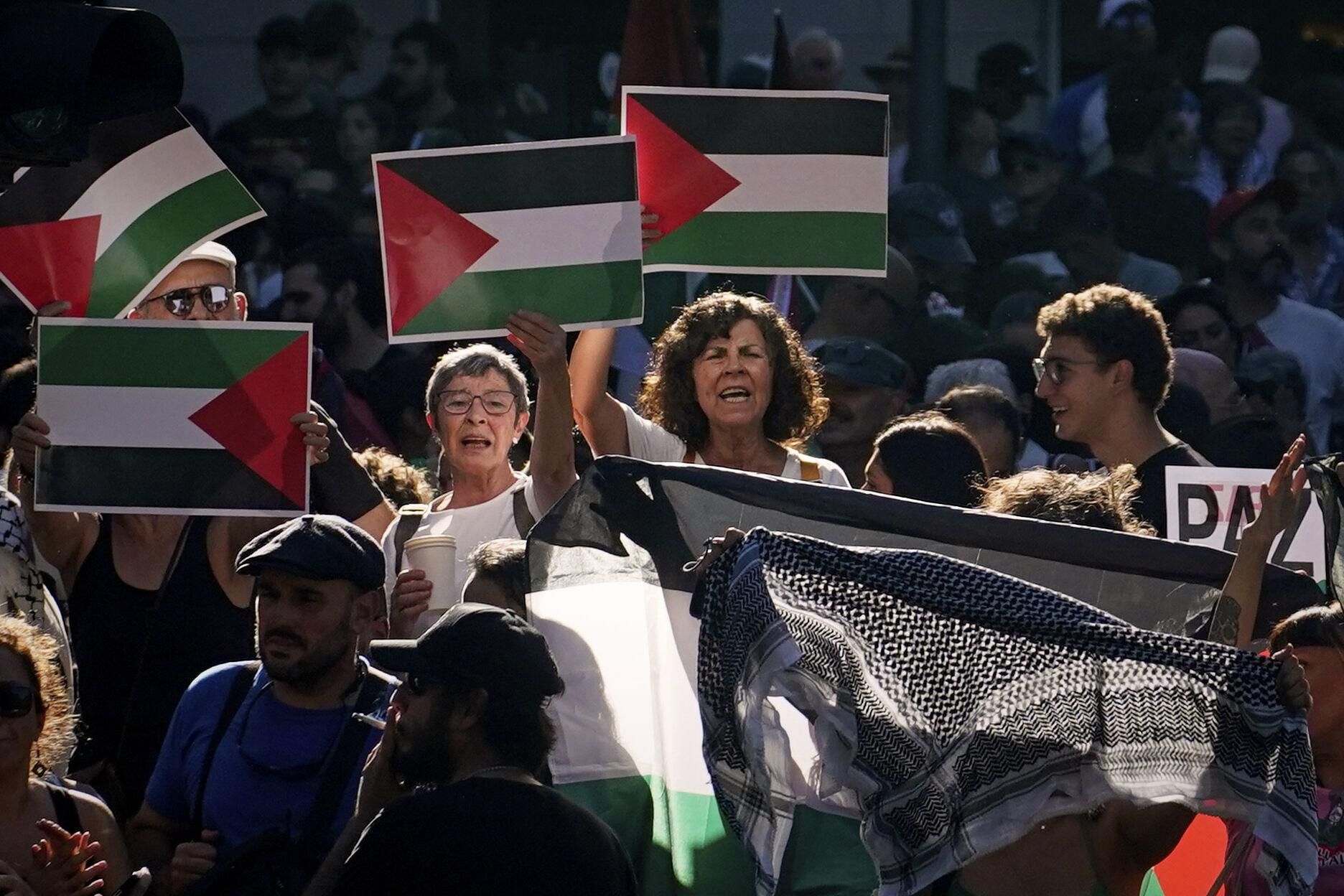 People shout slogans and hold Palestinian flags while protesting during the twenty-first stage of La Vuelta cycling race from Alalpardo to Madrid, Spain, Sunday, Sept. 14, 2025. (AP Photo/Andrea Comas)