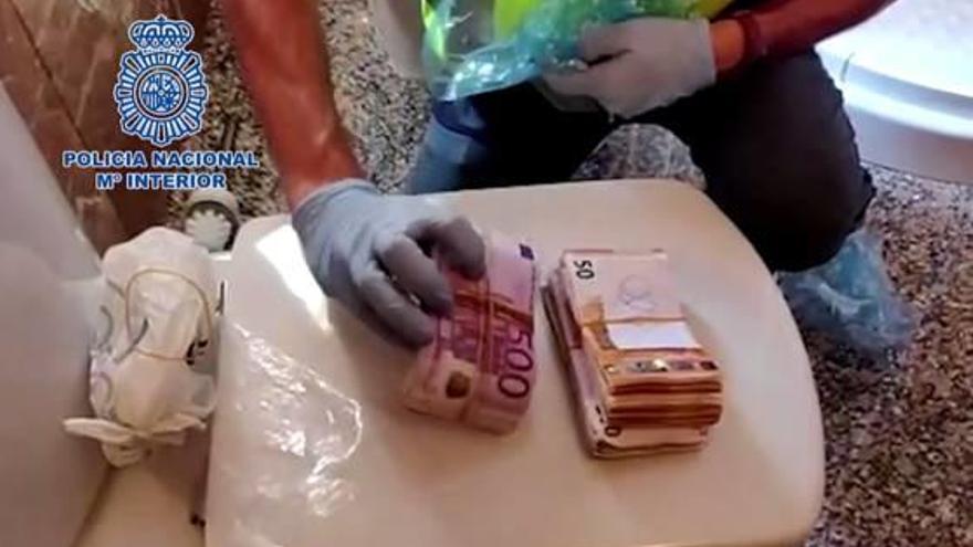 Un agente con dos paquetes de dinero que ocultaban en el retrete y sanitarios del cuarto de baño.