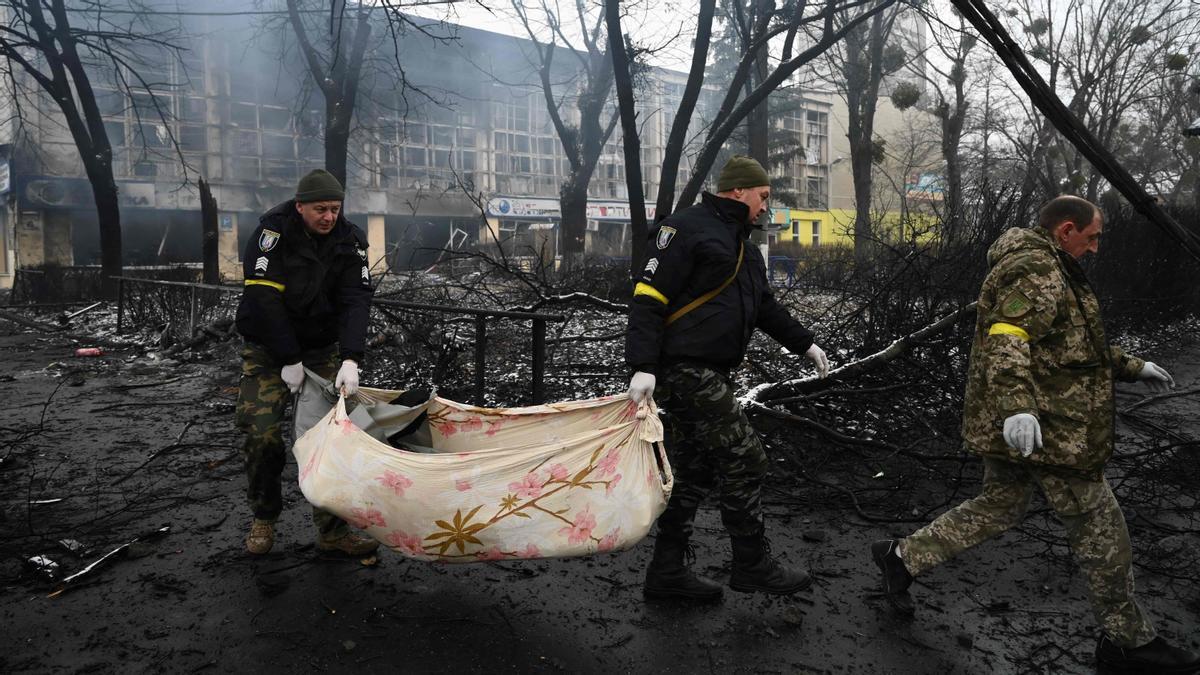 Agentes de policía retiran el cuerpo de un transeúnte muerto en el ataque aéreo de ayer que golpeó la principal torre de televisión de Kiev.