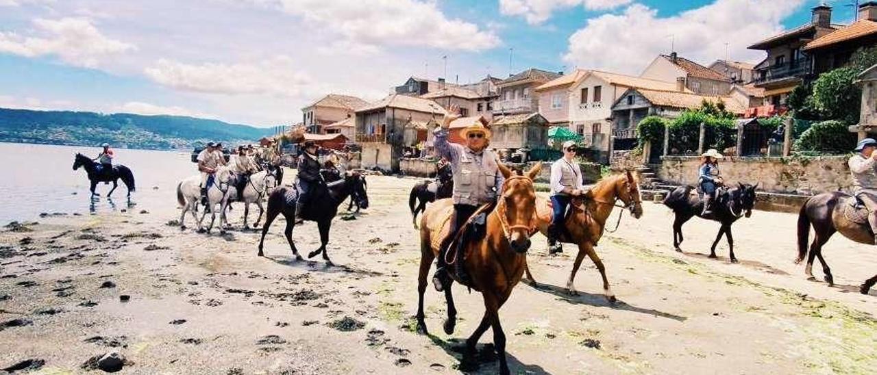 Los peregrinos a su paso por el arenal de Combarro, con los hórreos al fondo. // Caminos Galicia