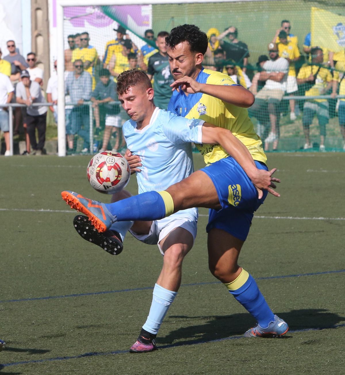 Millán protege un balón ante la oposición de un futbolista del Juventud de Cambados.