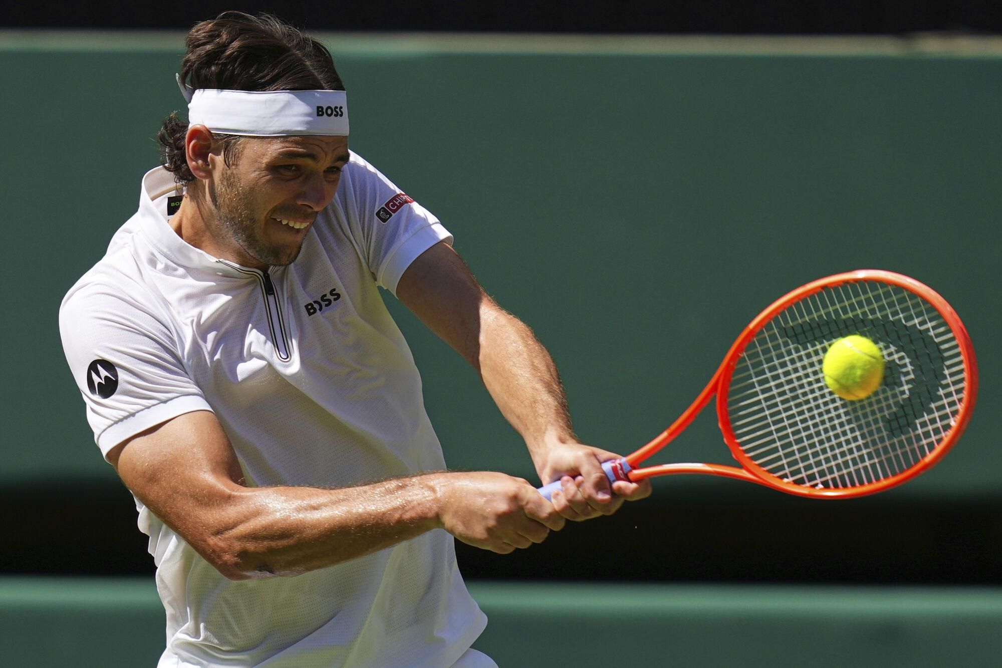 Taylor Fritz of the U.S. plays a return to Carlos Alcaraz of Spain during the men's semifinal singles match at the Wimbledon Tennis Championships in London, Friday, July 11, 2025.(AP Photo/Kirsty Wigglesworth). EDITORIAL USE ONLY/ONLY ITALY AND SPAIN