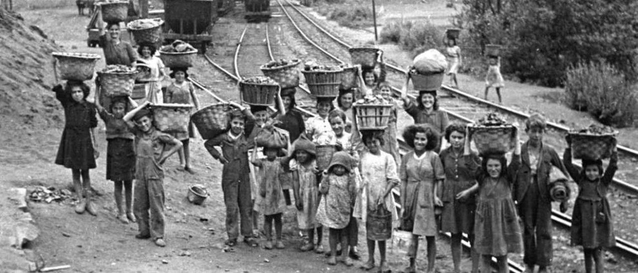 Un grupo infantil acarreando cestos de carbón junto a las vías del tren en la cuenca del Nalón, foto de Valentín Vega.