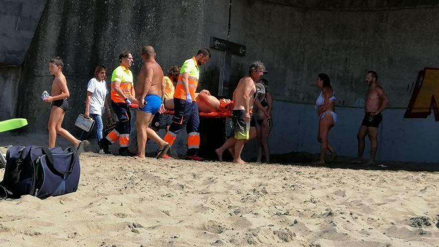 El personal médico traslada al herido en camilla, ayer, en la playa de Salinas.