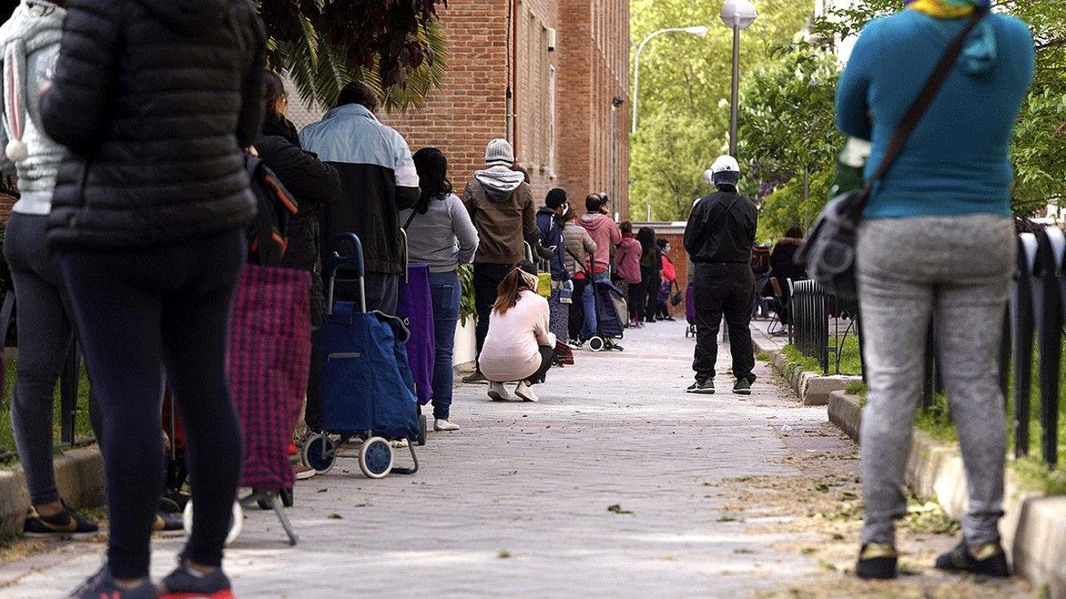 Numerosas personas esperan en una larga cola para recoger los alimentos que reparte la Fundación Madrina de Madrid, el 28 de abril