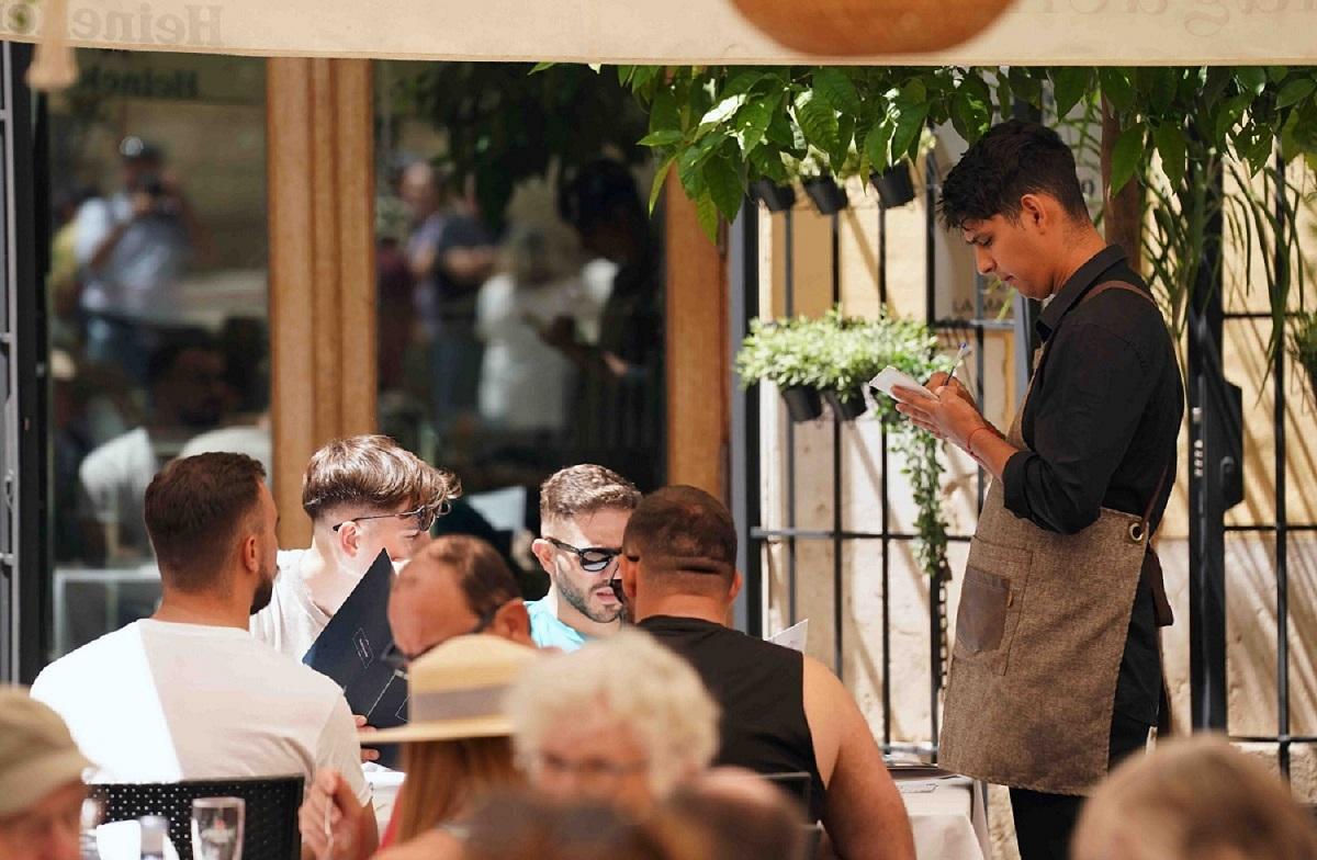 Clientes en un establecimiento de hostelería de Málaga atendidos por un camarero.