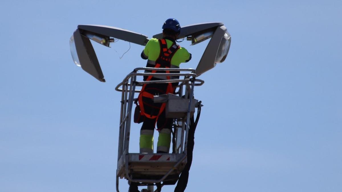 Un operario instala tecnología led en una farola de Federico Silva.