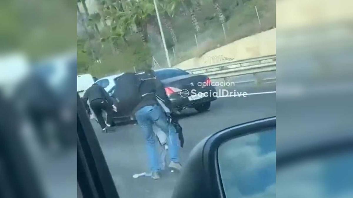 Dos homes recullen alguns dels bitllets de 50 euros que un conductor va llançar al mig de l&#039;autopista