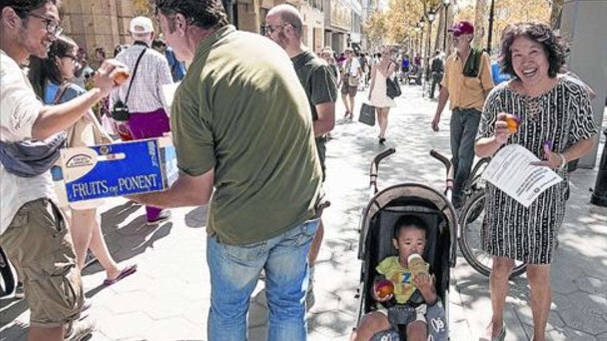 Un agricultor reparte nectarinas a barceloneses y turistas ayer en el paseo de Gràcia de Barcelona.