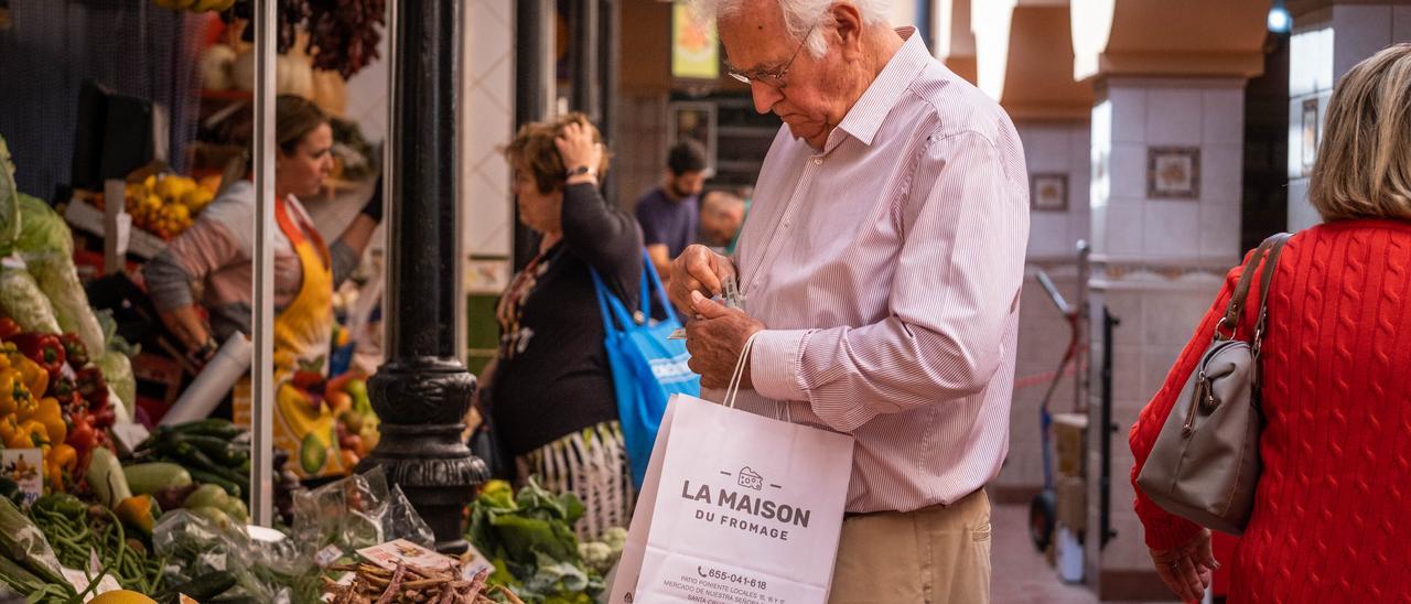 Un hombre busca en su cartera para pagar la compra en el mercado.