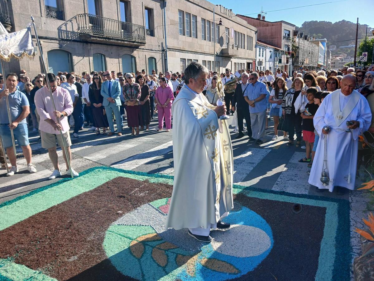 El cura de Bueu con el Santísimo en uno de los altares de Montero Ríos durante la procesión.