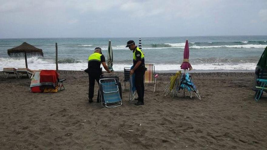 Agentes de la Policía Local retiran sombrillas en Torrox Costa.