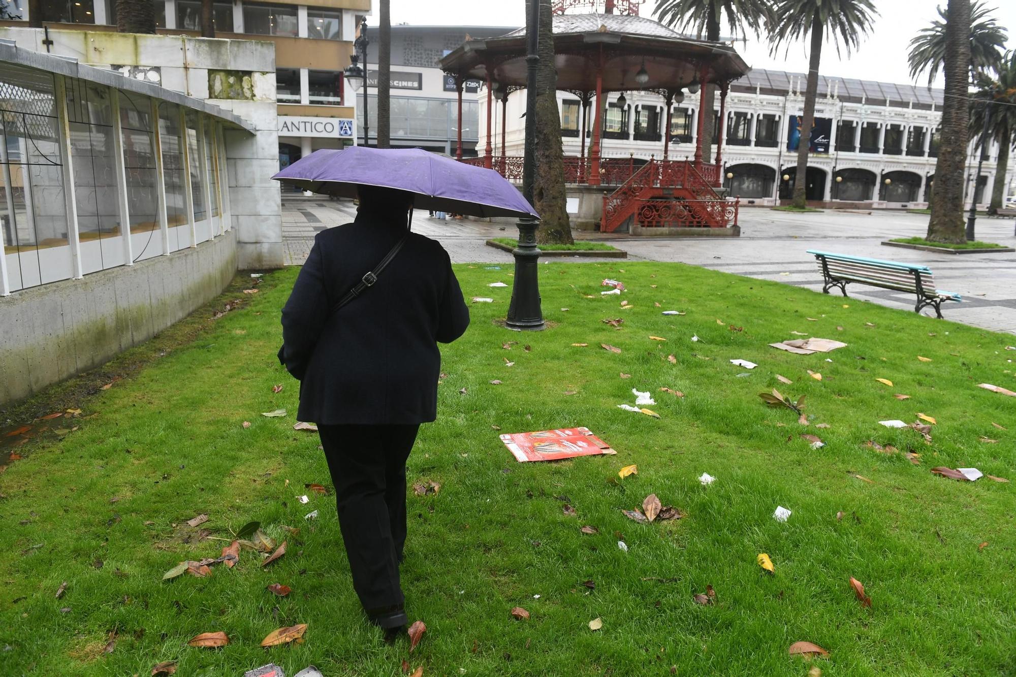 Una persona con paraguas en los jardines de Méndez Núñez, con hojas y papeles en el suelo por el viento durante la borrasca 'Karlotta'.