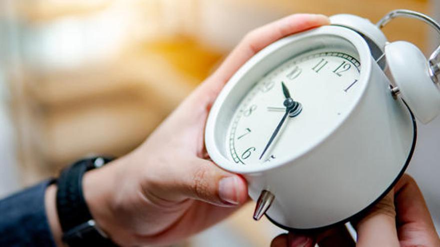 Una persona cambia la hora de un reloj.