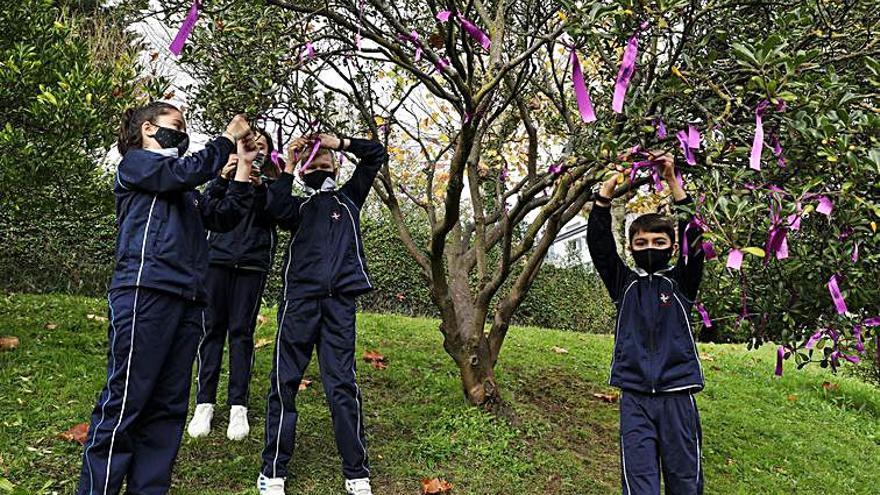 Los alumnos de las Dominicas cuelgan lazos morados de un árbol. | Juan Plaza