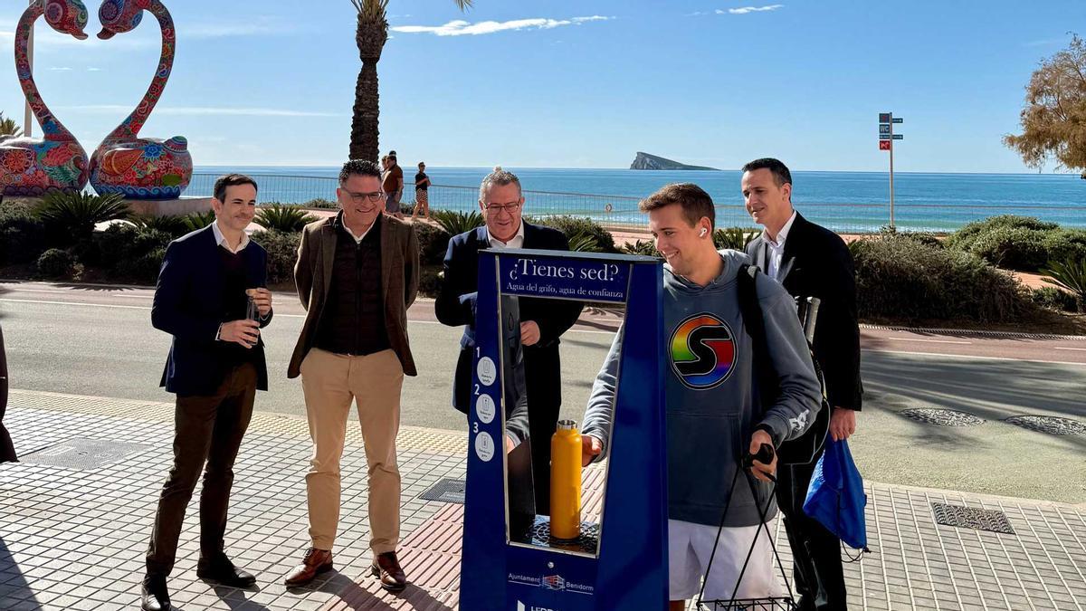 Un joven llena su botella en la primera fuente refrigerada de Benidorm, en presencia del alcalde, el edil de Ciclo del Agua y el gerente de Hidraqua