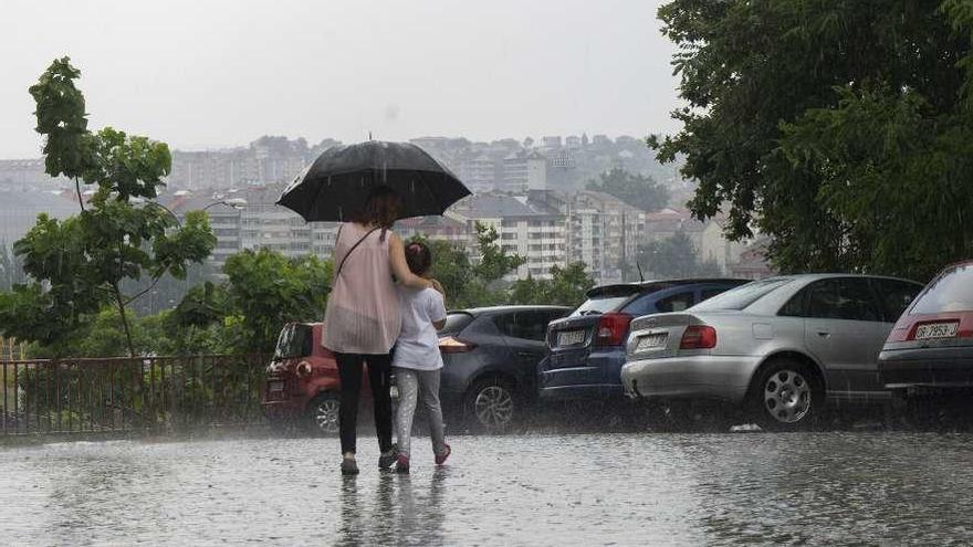 Una mujer y una niña, bajo el intenso aguacero en una calle de Ourense. // Enzo Sarmiento