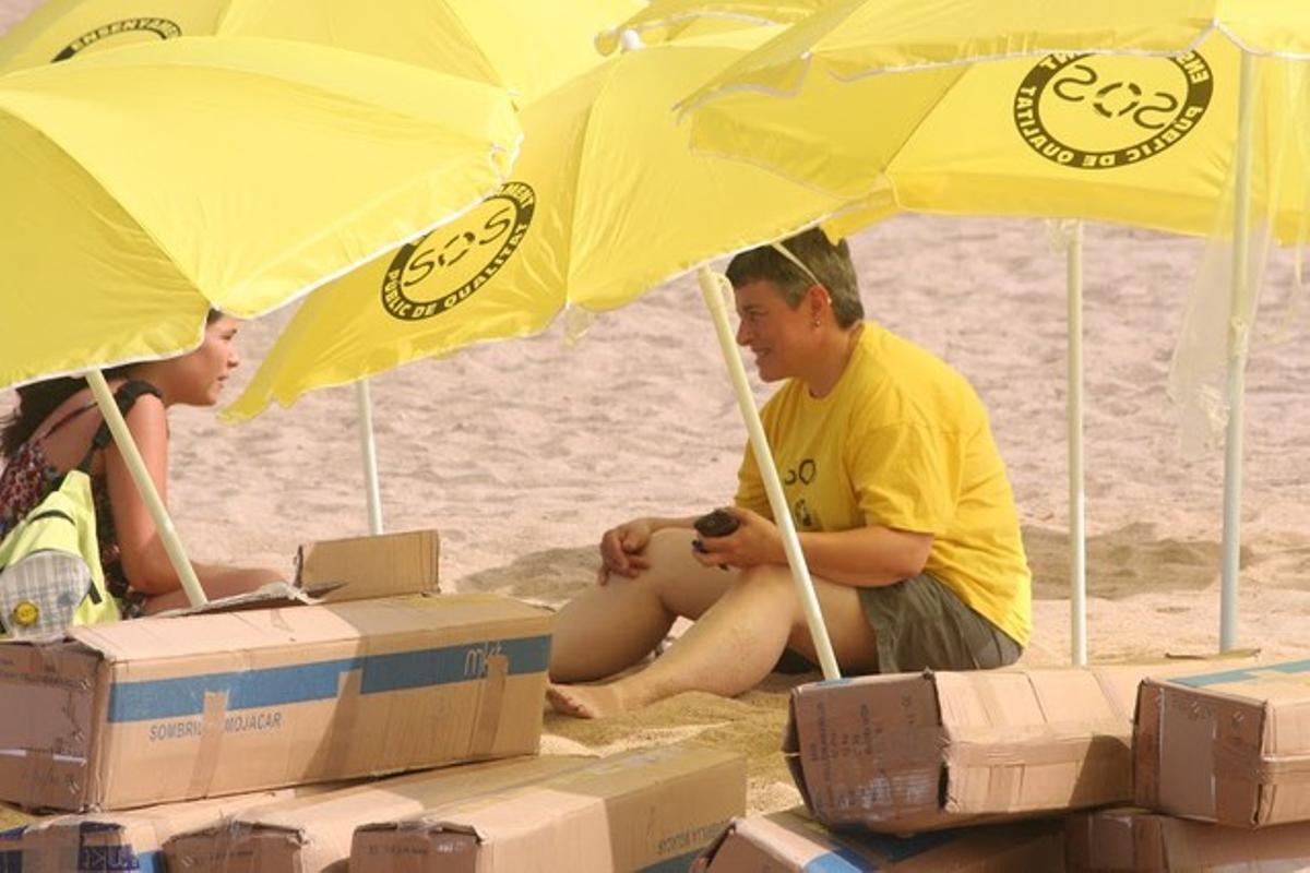 Membres de Badalona és mou repartint para-sols grocs a la platja del Pont del Petroli.