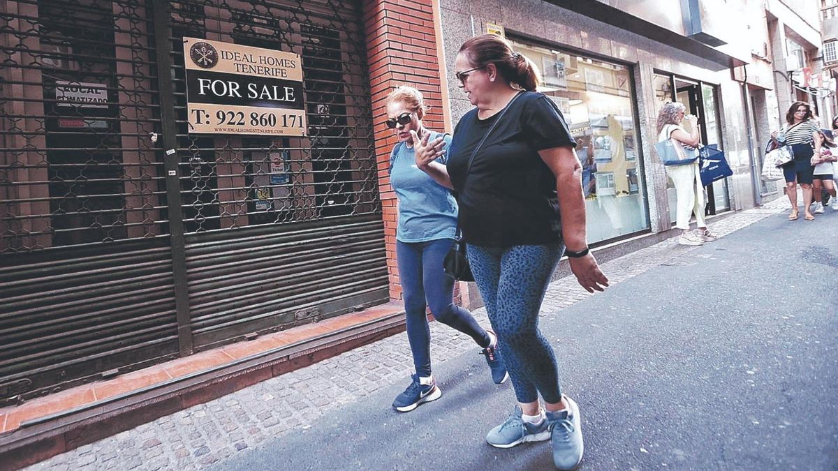 Dos mujeres pasan ante el local en venta de una inmobiliaria del Archipiélago