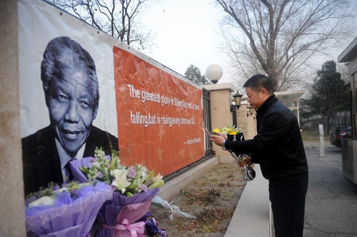 Un home diposita flors en memòria de Mandela davant de l’Ambaixada de Sud-àfrica a Pequín, aquest divendres.