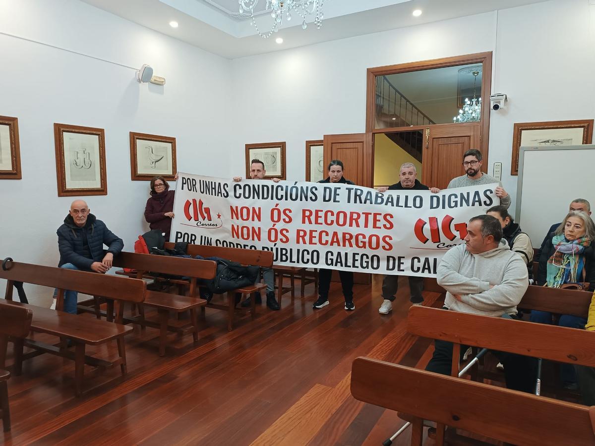 Representantes de la plantilla de Correos con una pancarta en el pleno de este lunes en Bueu.