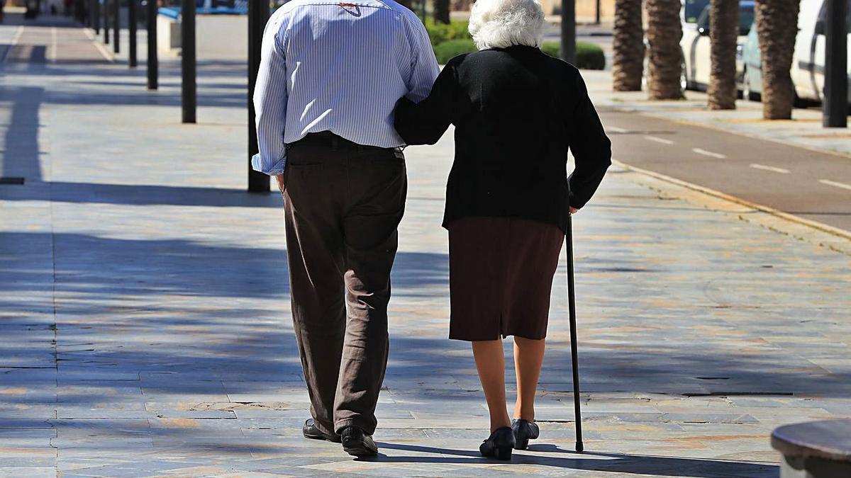 Una pareja de ancianos pasea sola por una calle de Cartagena.