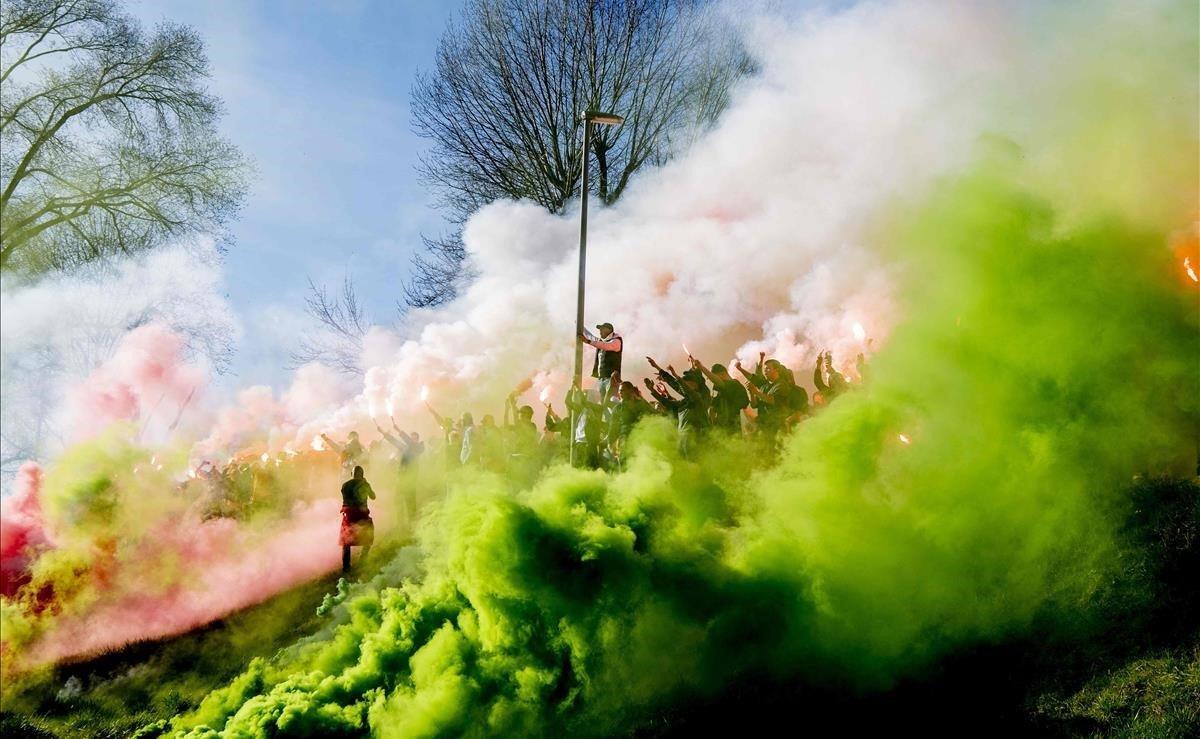 Los simpatizantes del equipo de fútbol holandés Feyenoord se reúnen el 26 de febrero de 2019 en el campo de entrenamiento para encender bengalas y cantar a los jugadores antes del enfrentamiento en la final de la Copa, entre Feyenoord y Ajax.