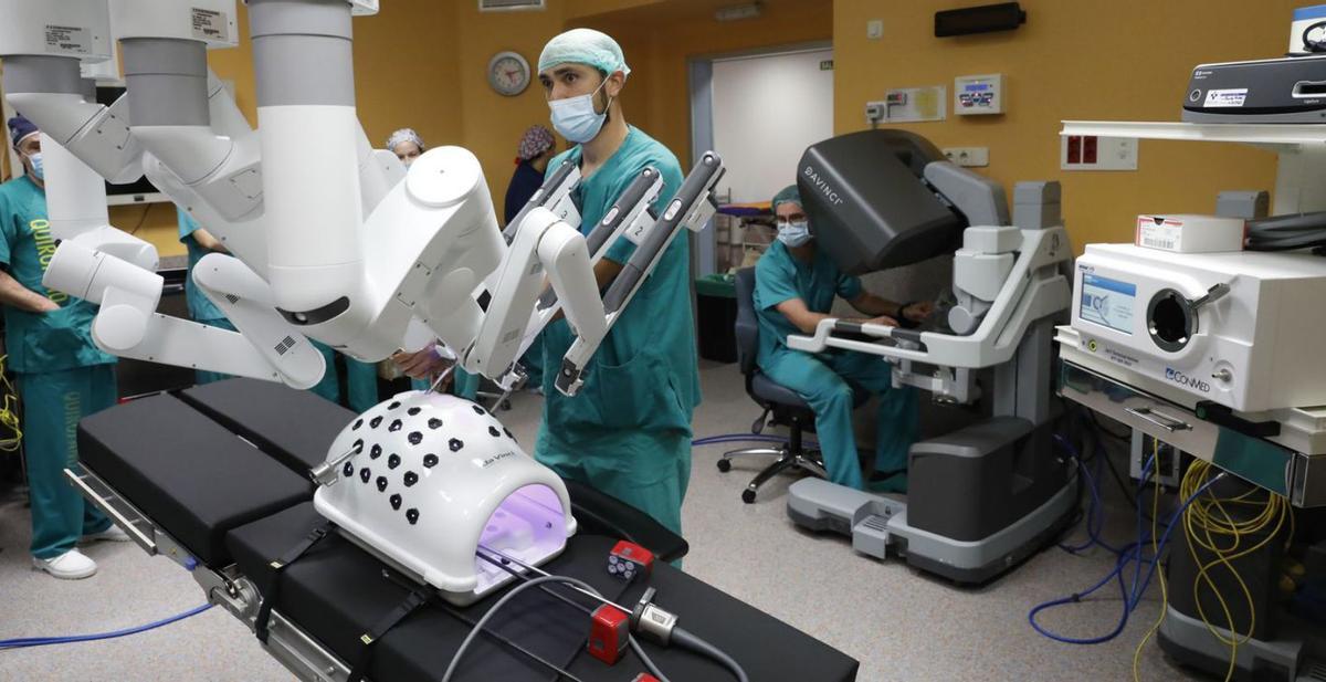 Gil, manejando los brazos del robot, y González, en la consola, en uno de los ensayos para la primera cirugía robótica del hospital gijonés. | Marcos León