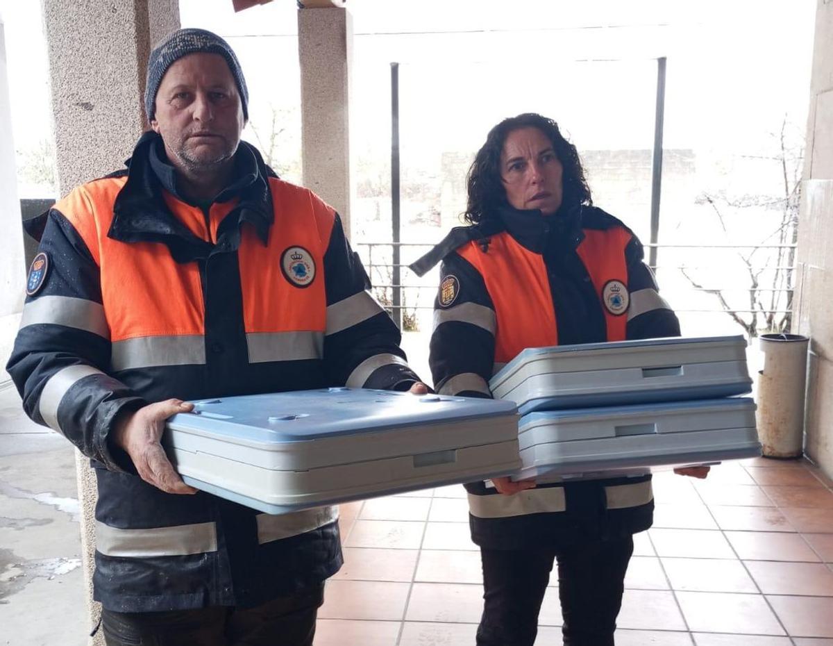 Dos de los voluntarios Protección Civil de Sarreaus con dos menús. | Cedida CDR O Viso