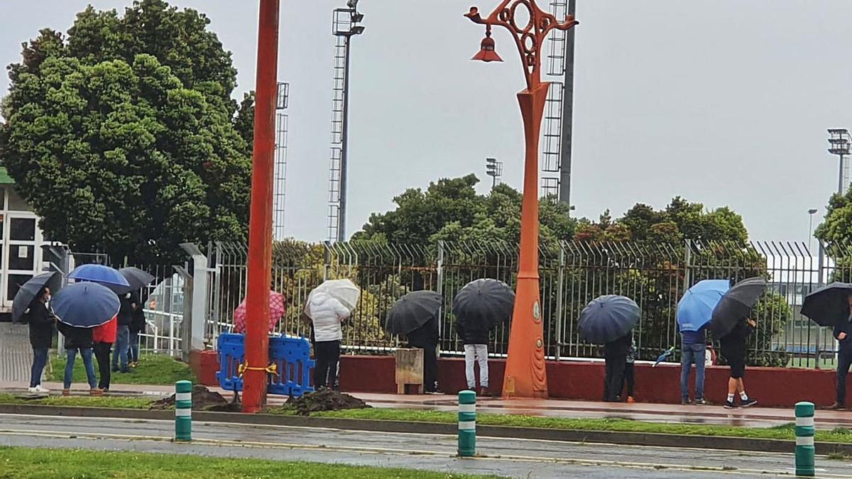 Familiares de jugadores de fútbol observan un partido en A Torre desde el exterior del recinto.