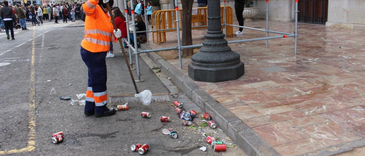 Una empleada de limpieza recoge latas de cerveza después de la «mascletà» del domingo.