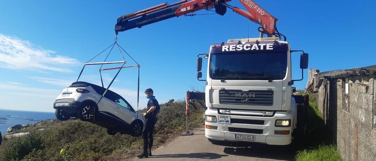 Una grúa de asistencia retira el coche que se salió de la vía y volcó por un terraplén.