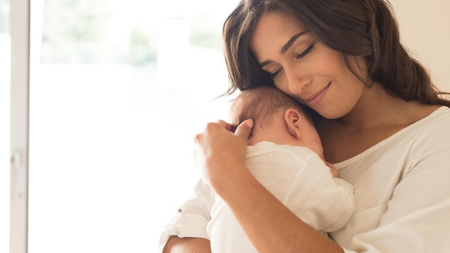 Una madre calma a su bebé en sus brazos.