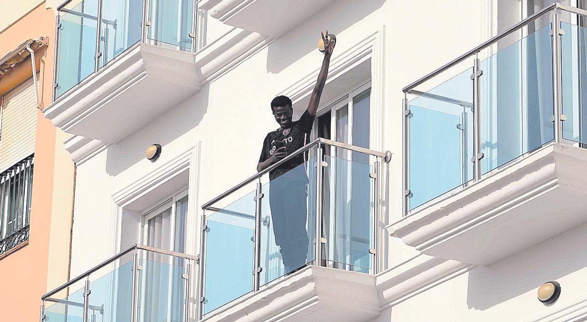 Un joven inmigrante saluda desde su habitación del hotel de El Morche.