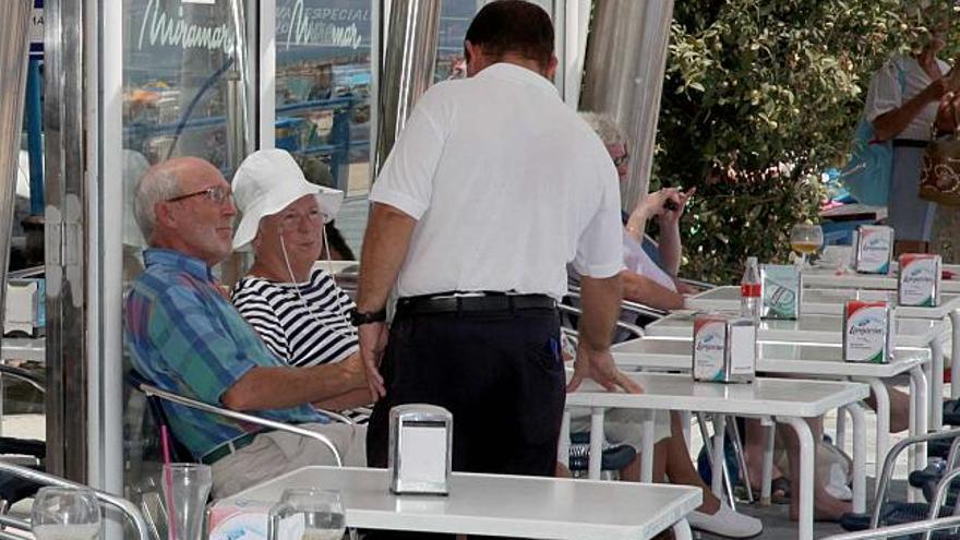 Un camarero atiende una terraza en una cafetería del Paseo de Gómiz en la playa del Postiguet esta semana.