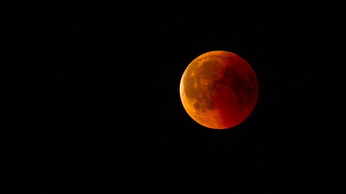 Imagen de archivo de un eclipse lunar, en el momento en el que la Luna comienza a ser tapada por la Tierra y recibe parte de su reflejo rojizo