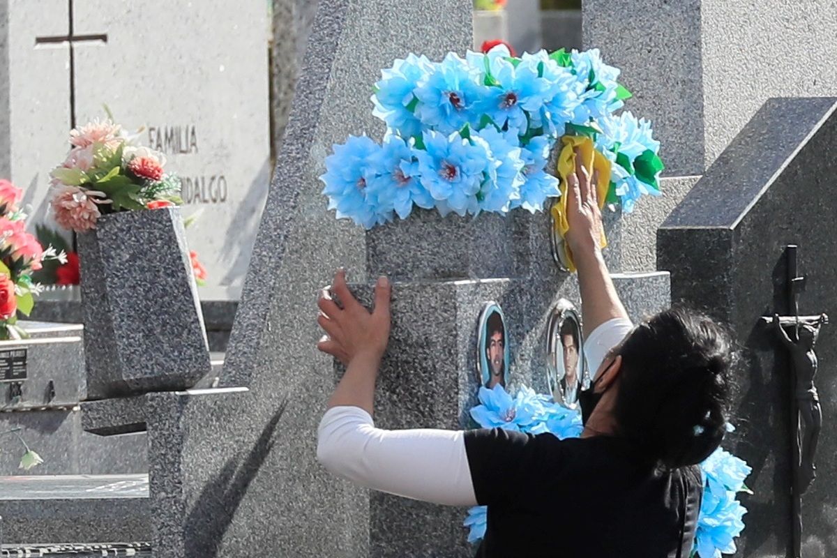 Una mujer limpia una lápida en el cementerio de La Almudena.