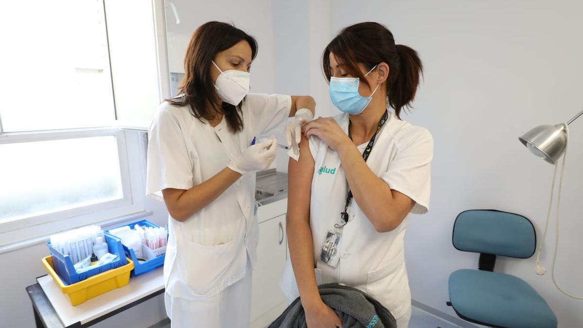 Una sanitaria vacuna contra la gripe a una compañera.