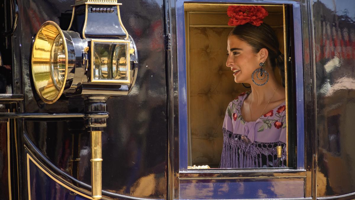 SEVILLA, 14/04/2024.-Una mujer vestida de flamenca en un carruaje, este domingo en el Real de la Feria de Abril de Sevilla .-EFE/ Raúl Caro.