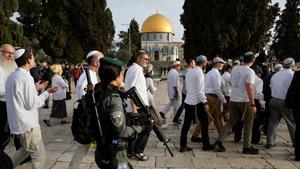 Fieles judíos cruzan la Explanada de las Mezquitas en Jerusalén ante la vigilancia de una militar del ejército de Israel, este sábado 9 de abril de 2023. 