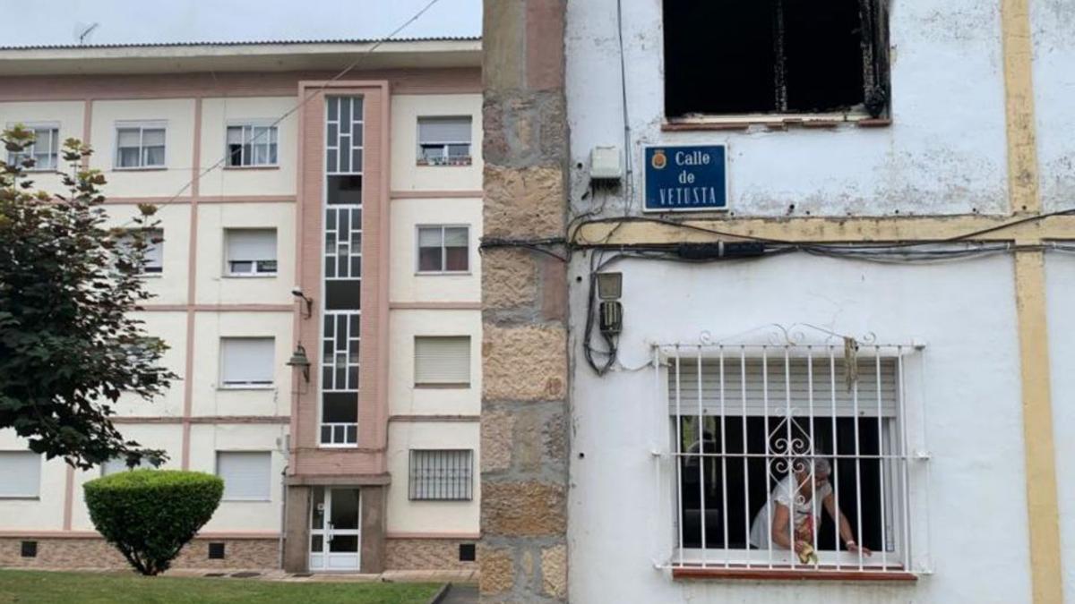 Una mujer limpia una ventana del piso inferior al quemado.