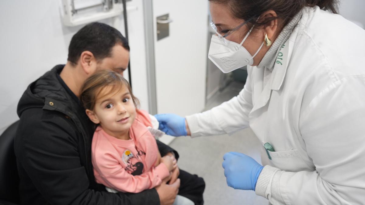 Una niña se vacuna contra la gripe en el centro de salud del Centro.