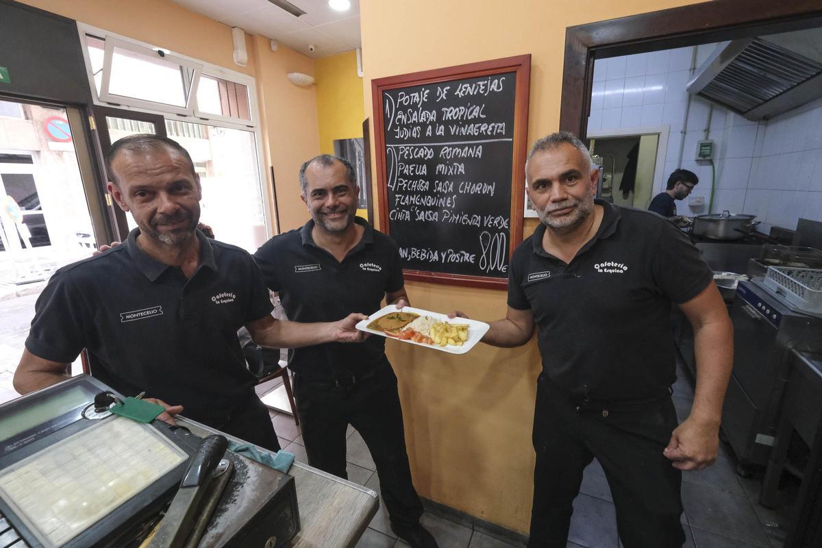 Los hermanos Suárez, junto a otro trabajador, sostienen uno de los platos del menú del día.