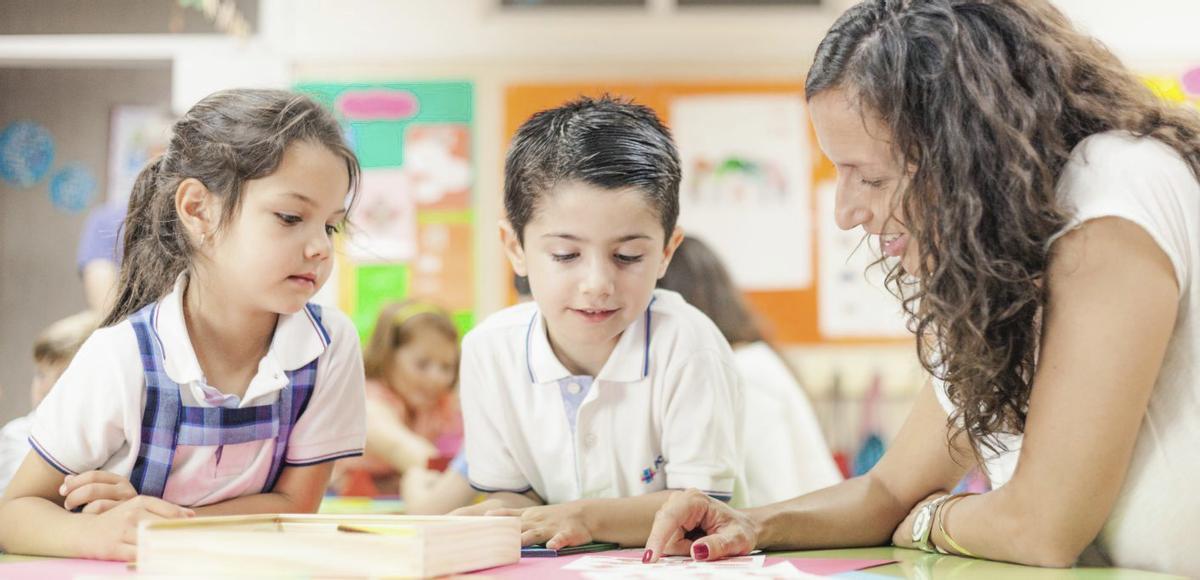 Dos estudiantes con una profesora en clase.