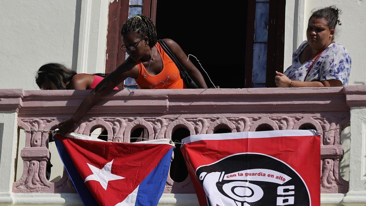 Mujeres colocan banderas en un balcón.