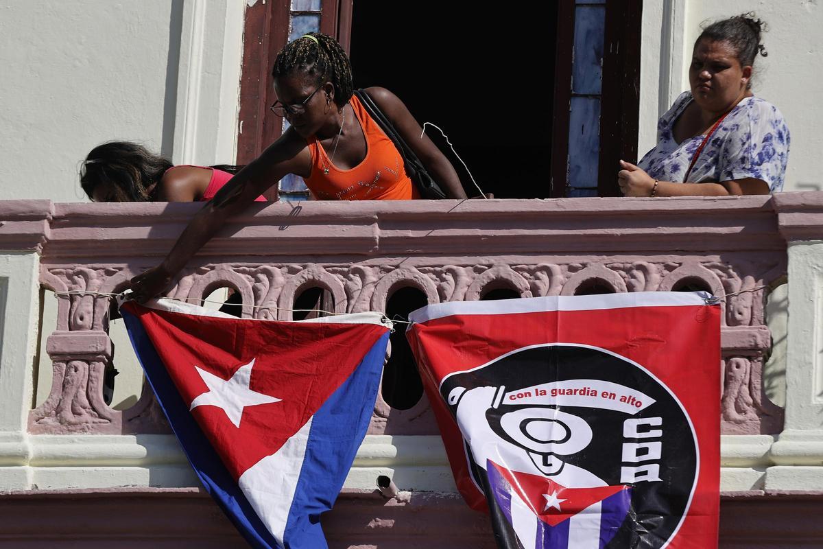 Mujeres colocan banderas en un balcón.